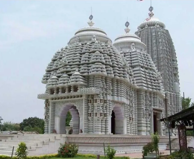 “White stone Hindu temple with intricate carvings and traditional Indian architectural design.”